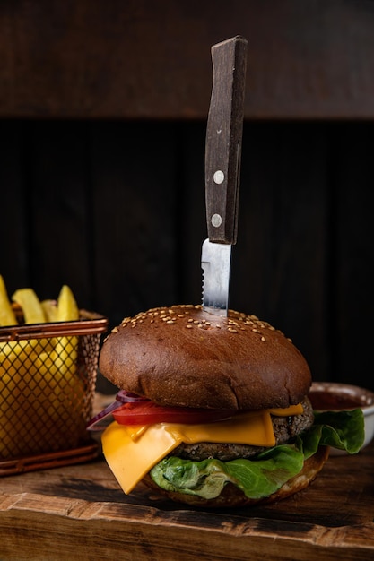 Фото Гамбургер с сырной котлетой, салатом, томатным соусом и картофелем фри