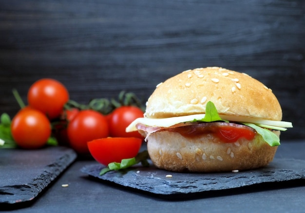 Hamburger with cheese ham herbs and ketchup fresh tomatoes Closeup