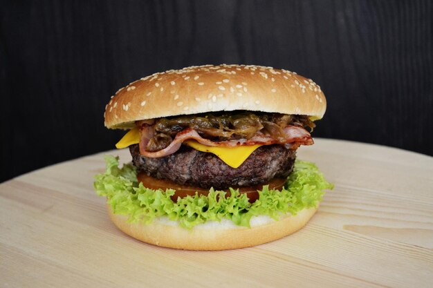 a hamburger with cheese and lettuce on it is on a wooden table.