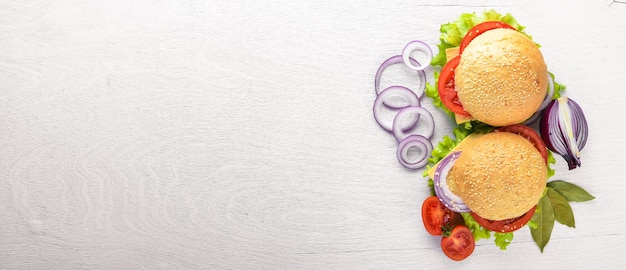 Hamburger with cheese, meat, tomatoes and onions and herbs. On Wooden background. Top view. Free space.