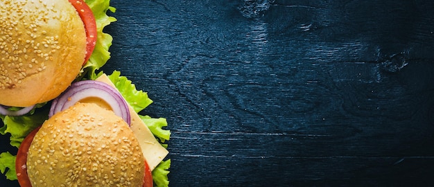 Гамбургер с сыром, мясом, помидорами и луком и зеленью. На деревянном фоне. Вид сверху. Свободное место.