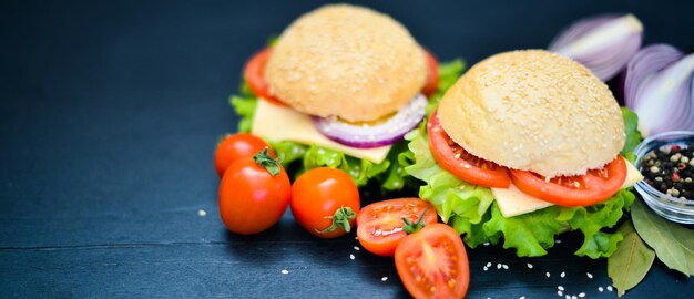 Гамбургер с сыром, мясом, помидорами, луком и зеленью на деревянном фоне Вид сверху Свободное пространство