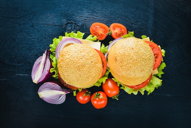 Hamburger with cheese meat tomatoes and onions and herbs On Wooden background Top view Free space