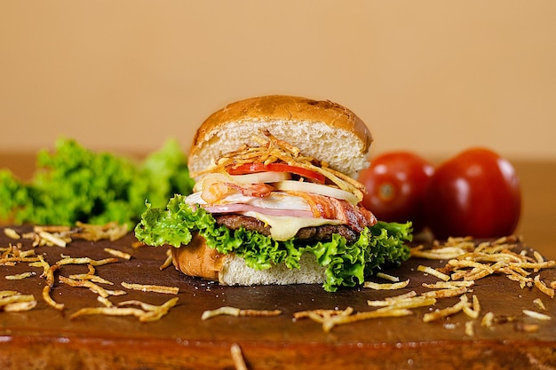 Foto un hamburger con sopra formaggio, pomodoro e lattuga.