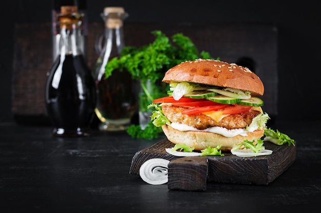 Hamburger with chicken burger meat cheese tomato cucumber and lettuce on wooden background Tasty burger Close up