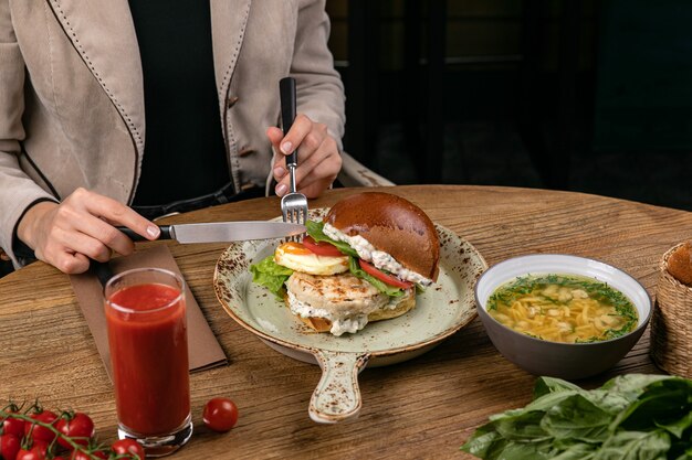 Hamburger with chicken cutlet soup tomato juice basil tomatoes on the table