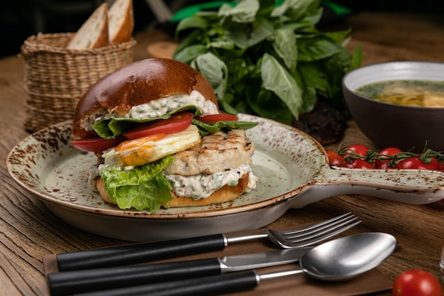 Hamburger with chicken cutlet soup tomato juice basil tomatoes on the table