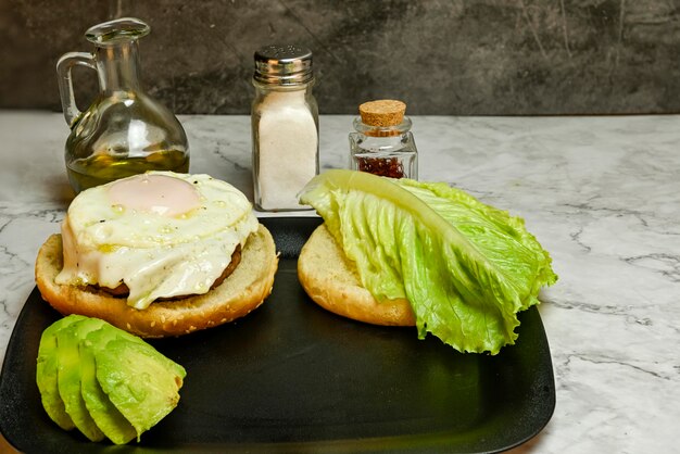 Hamburger with fried egg lettuce and avocado