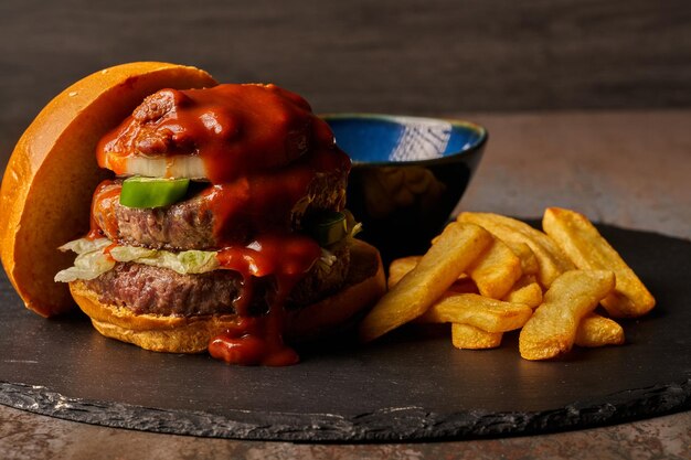 フライドポテトオニオンチリと肉とジャラペノスバーベキューソースのダークスタイルの食べ物とハンバーガー