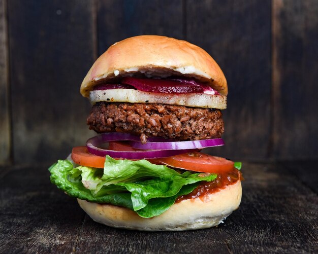 a hamburger with lettuce and tomato on a wooden background.