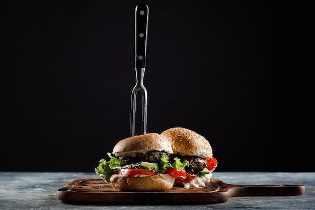 Photo hamburger with meatballs on a black. with a fork stuck.