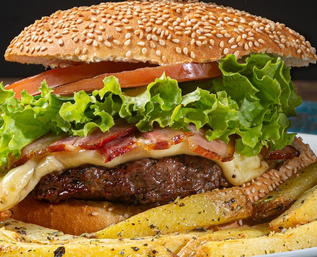 Гамбургер с плавленым сыром, жареным беконом, майонезом, салатом, помидорами и картофелем фри