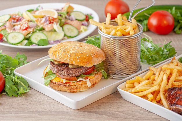 Hamburger with potatoes, salad and grilled meat dish