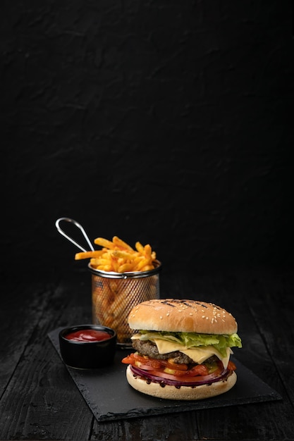 Hamburger with sauce and french fries on a dark wooden table