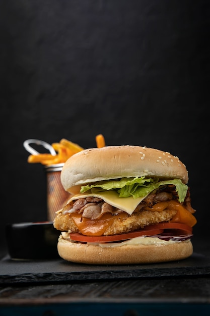 Hamburger with sauce and french fries on a dark wooden table