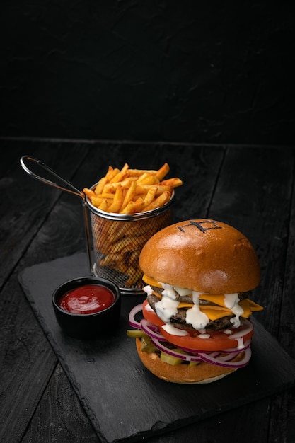 Hamburger with sauce and french fries on a dark wooden table