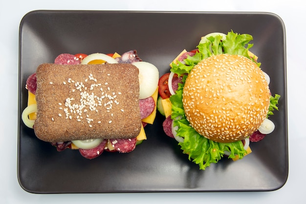 Hamburger with vegetables and sausage on a gray table. Fast food and breakfast. Calories and diet.