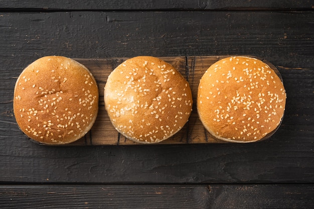 Hamburgerbrood Huisgemaakte Brioche Hamburgerbroodjes set, op houten serveerplank, op zwarte houten tafel