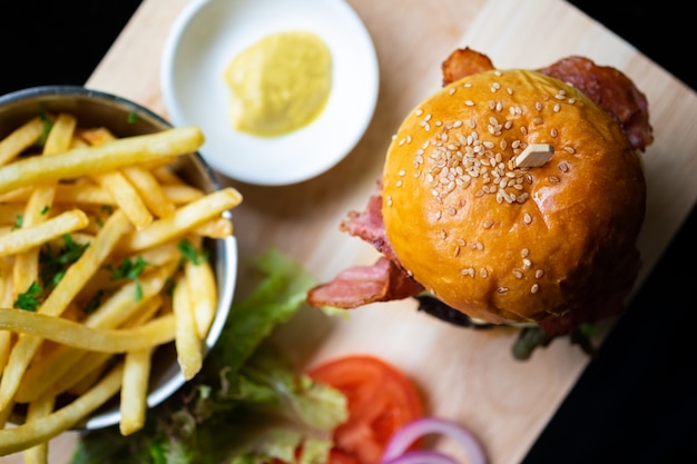 Hamburgers and French fries on the wooden tray.