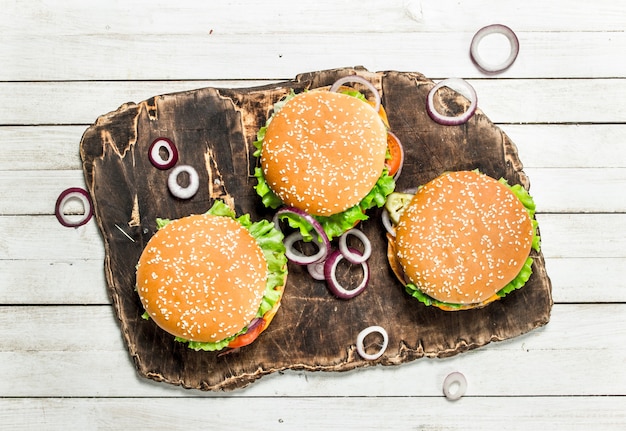 Hamburgers met rundvlees en groenten op een snijplank op een witte houten achtergrond