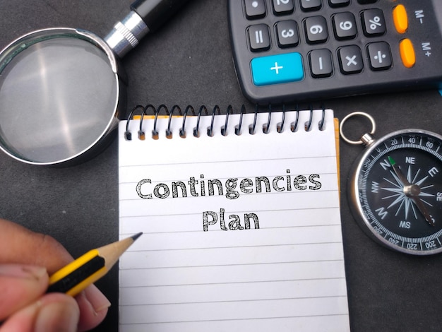 Hamd holding pencil wriiten on notebook with the word Contingencies Plan Business concept