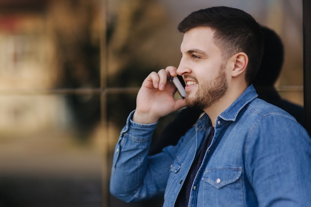 Photo hamdsome beard man taking a call on his phone.