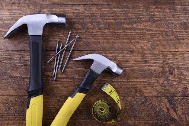 Hamer ijzer, centimeter tape en spijkers op houten tafel