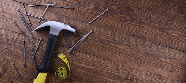 Hamerijzer, centimeter tape en nagels op houten tafel