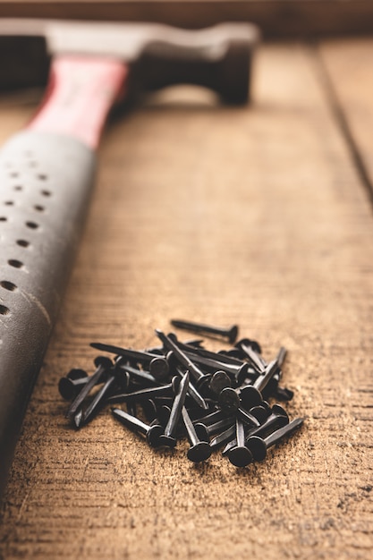 Hammer and black nails on wood table. Old tools. Copy space.