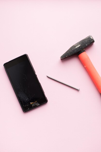 Hammer en mobiele telefoon met gebroken scherm
