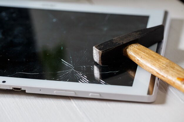 The hammer hits the broken touchscreen tablet, suggesting that it is about to replace it. Broken glass tablet repair