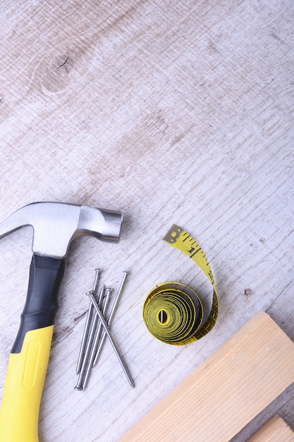 Hammer iron,centimeter tape and nails on wooden table