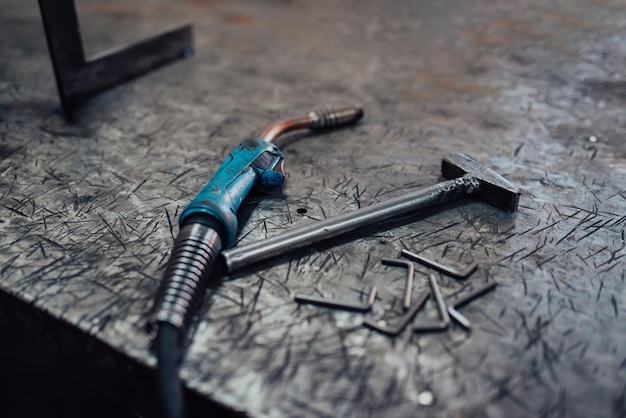 A hammer and a modern welding machine on a steel industrial table