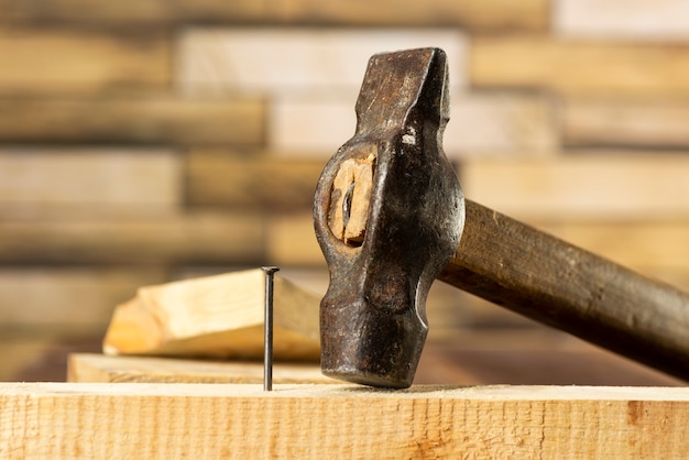 Photo hammer a nail into a wooden board, work, carpentry, close up hammering a nail