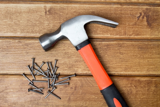 Hammer and nails scattered on wooden