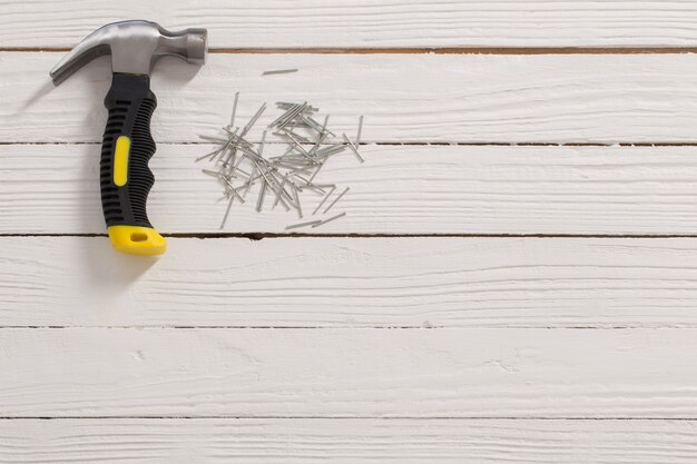 Hammer and nails on white wooden surface