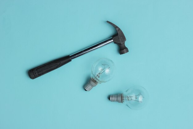 Hammer and old light bulbs on a blue background