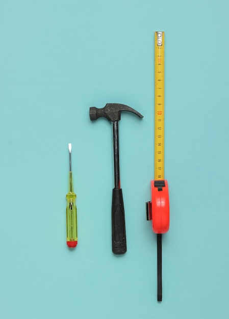 Hammer screwdriver and ruler on blue background