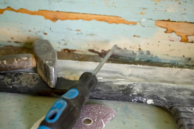 Hammer screwdriver a spatula on a dirty wooden shelf tools for the repair of the premises