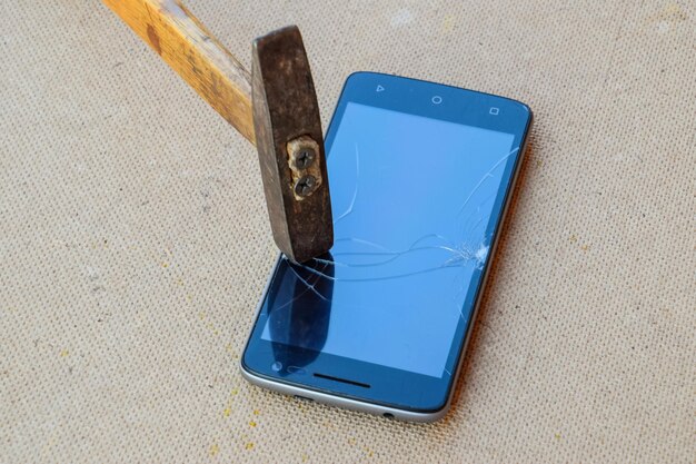 Foto il martello e lo smartphone lo schermo dello smartphone è rotto