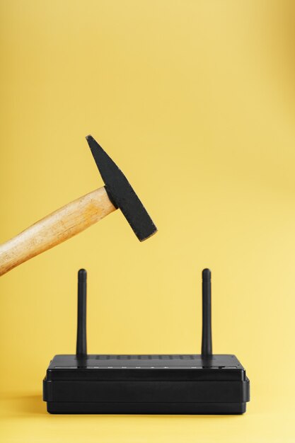 Martello sul router wi-fi per la distruzione su uno sfondo giallo