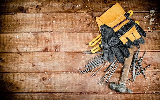 Hammer with nails and gloves on the table