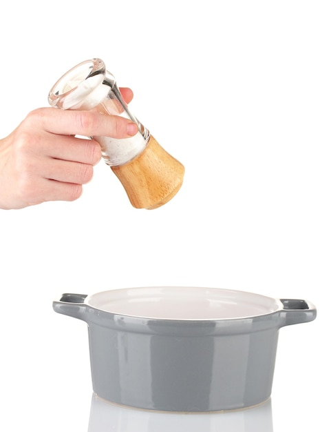 Hand adding salt using salt shaker isolated on white