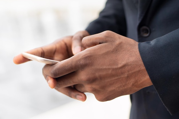 Mano dell'uomo d'affari africano che utilizza l'applicazione mobile per smartphone