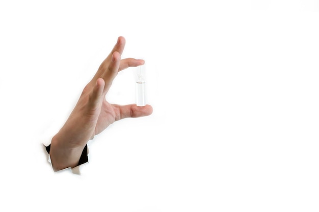 In the hand an ampoule with the medicine on a white background