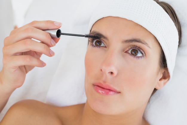 Hand applying mascara to beautiful woman