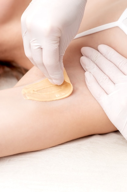 Foto applicare a mano la pasta di cera sulla depilazione dell'ascella o sull'ascella dell'epilazione femminile con pasta di zucchero liquida