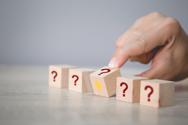 Hand arranging flips wood block stacking with icon question mark and lamp,thinking with question mark concept.