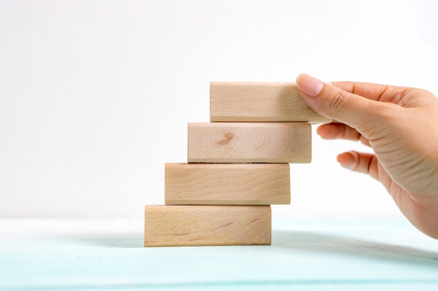 Hand arranging wood block stacking as step stair. business\
concept for growth success process. stairs up as a symbol of career\
growth up or business success.