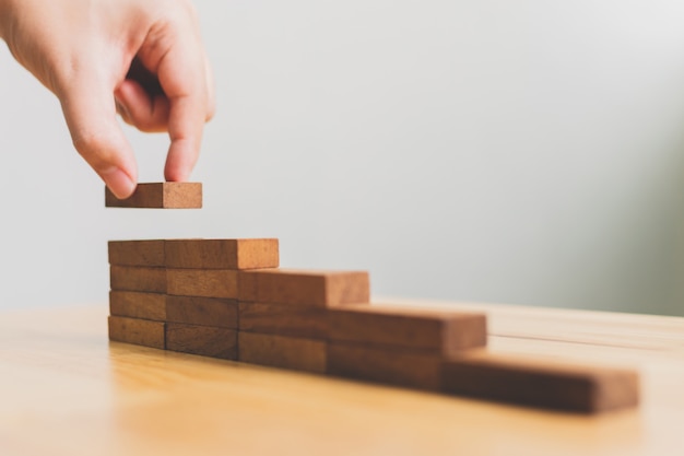 Photo hand arranging wood block stacking as step stair. ladder career path concept for business growth success process